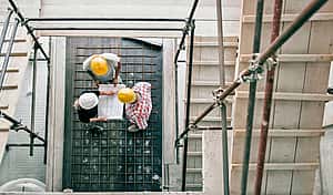 young trade workers discussing plans of tool leasing with Florian Gap Trust on clean construction sight with hard hats on